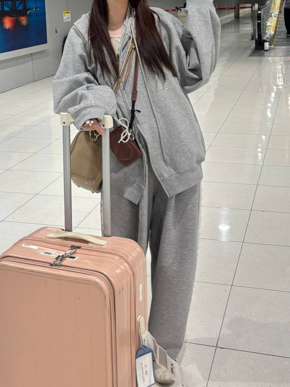 グレー系のスウェットパンツ、グレー系のパーカー、ゴールド系のボストンバッグを着用したレディースの冬コーディネートの4枚目の写真