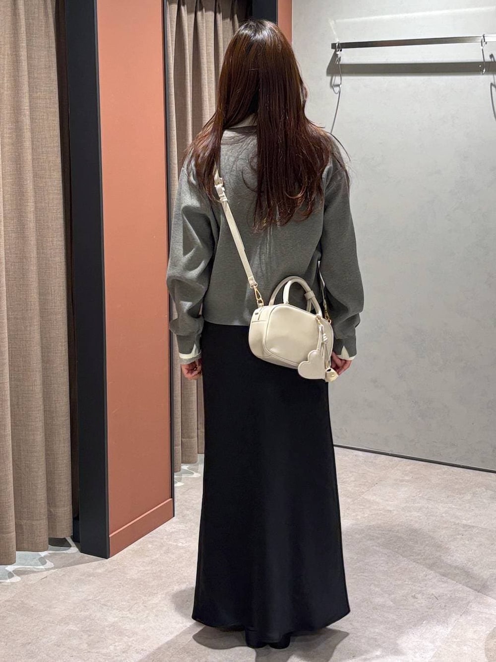 ブラック系のスカート、ホワイト系のボストンバッグ、ブラック系のブーツを着用したレディースの冬コーディネートの3枚目の写真