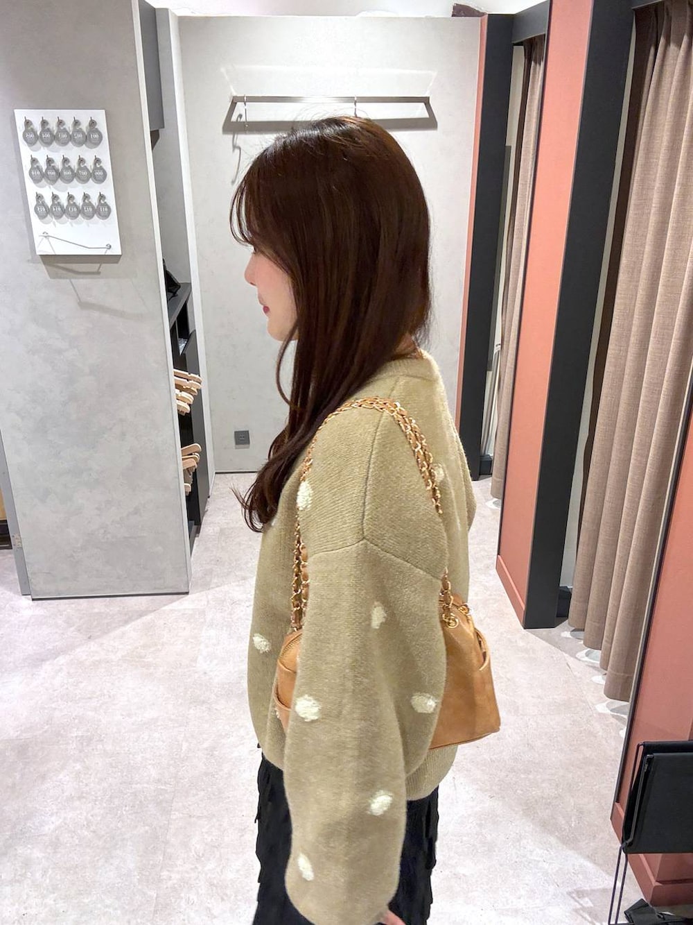 ブラック系のスカート、ベージュ系のショルダーバッグ、ゴールド系のニット/セーターを着用したレディースの冬コーディネートの2枚目の写真