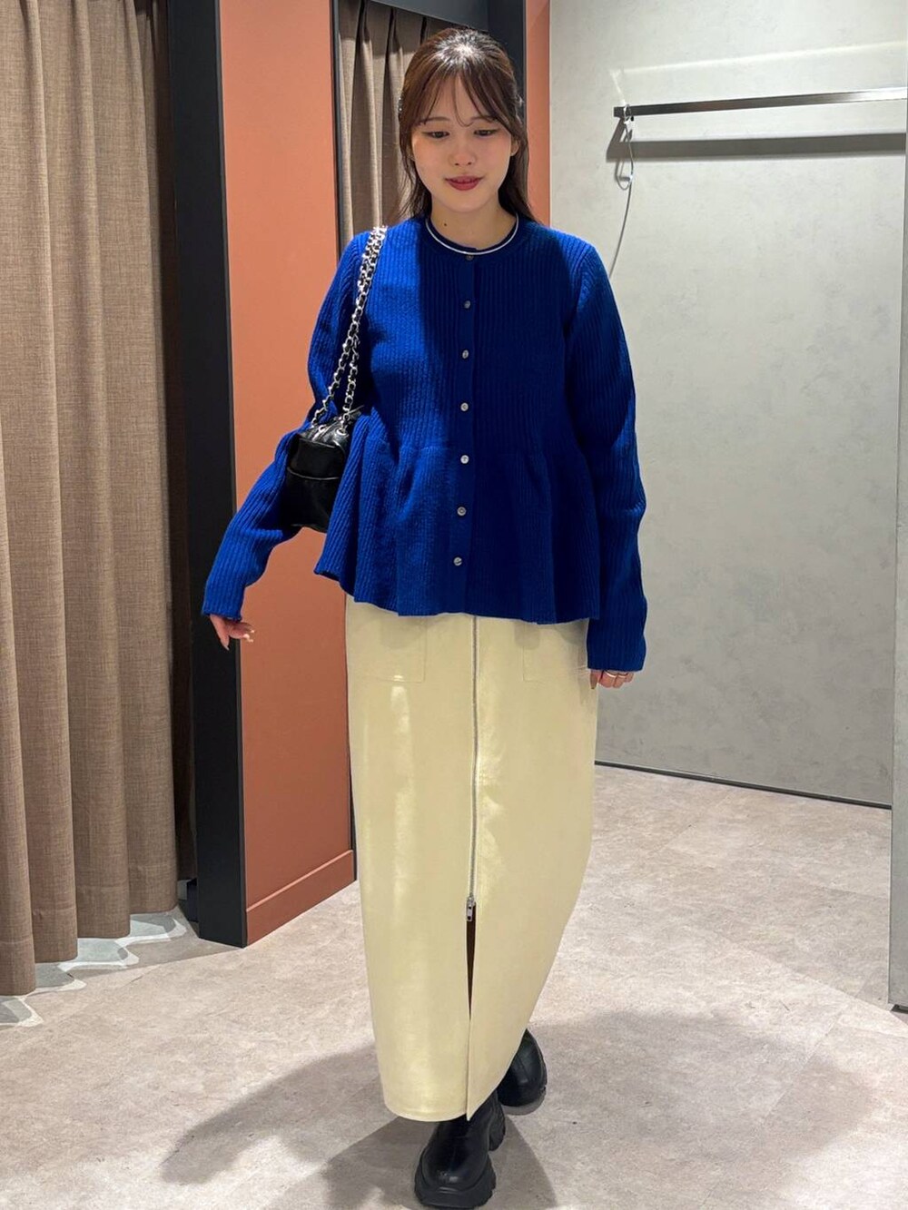 ブラック系のブーツ、ホワイト系のスカート、ブルー系のカーディガン/ボレロを着用したレディースの秋コーディネートの4枚目の写真