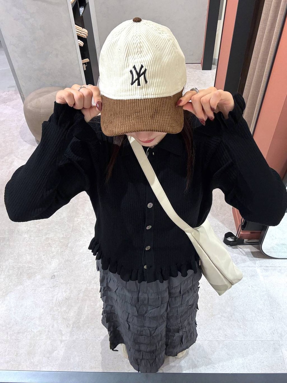 ホワイト系のショルダーバッグ、ホワイト系のスニーカー、グレー系のスカートを着用したレディースの秋コーディネートの2枚目の写真