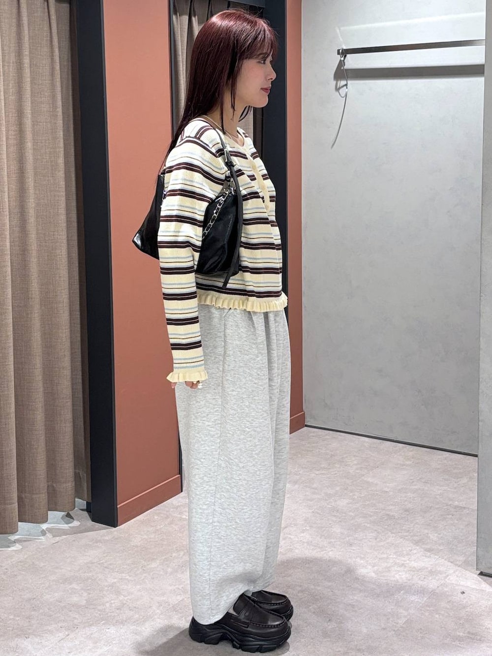 グレー系のスウェットパンツ、ブラック系のショルダーバッグ、ブラウン系のローファーを着用したレディースの冬コーディネートの3枚目の写真