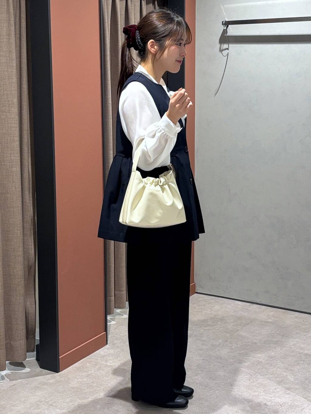 ブラック系のブーツ、ホワイト系のショルダーバッグ、ブルー系のスラックスを着用したレディースの冬コーディネートの2枚目の写真