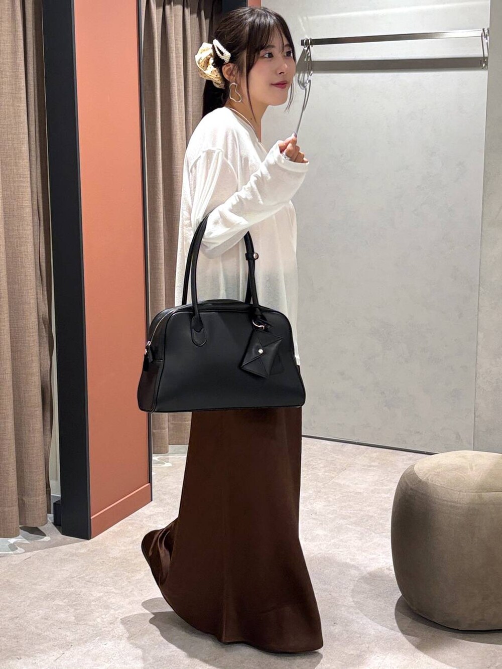 ブラウン系のスカート、ピンク系のスニーカー、ブラック系のボストンバッグを着用したレディースの秋コーディネートの2枚目の写真