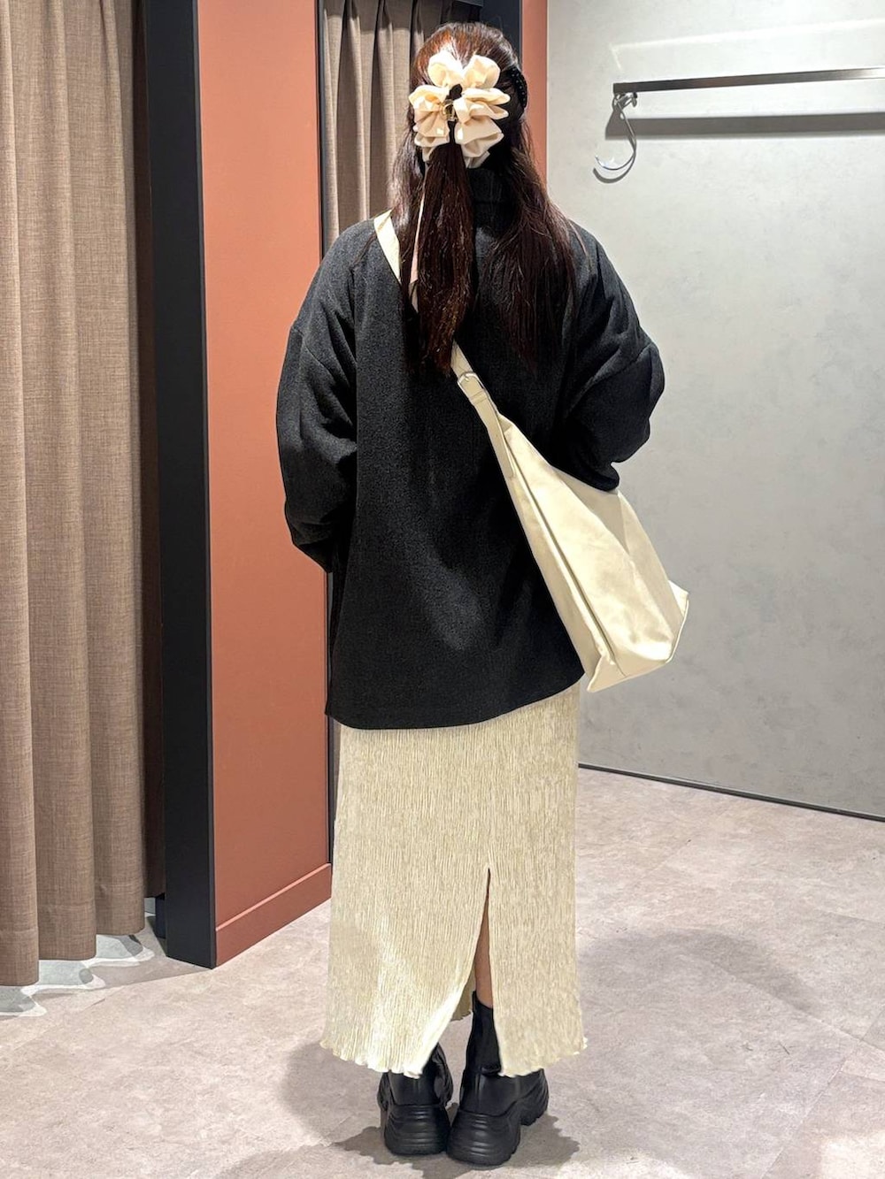 ブラック系のショルダーバッグ、ブラック系のブーツ、ホワイト系のスカートを着用したレディースの冬コーディネートの3枚目の写真