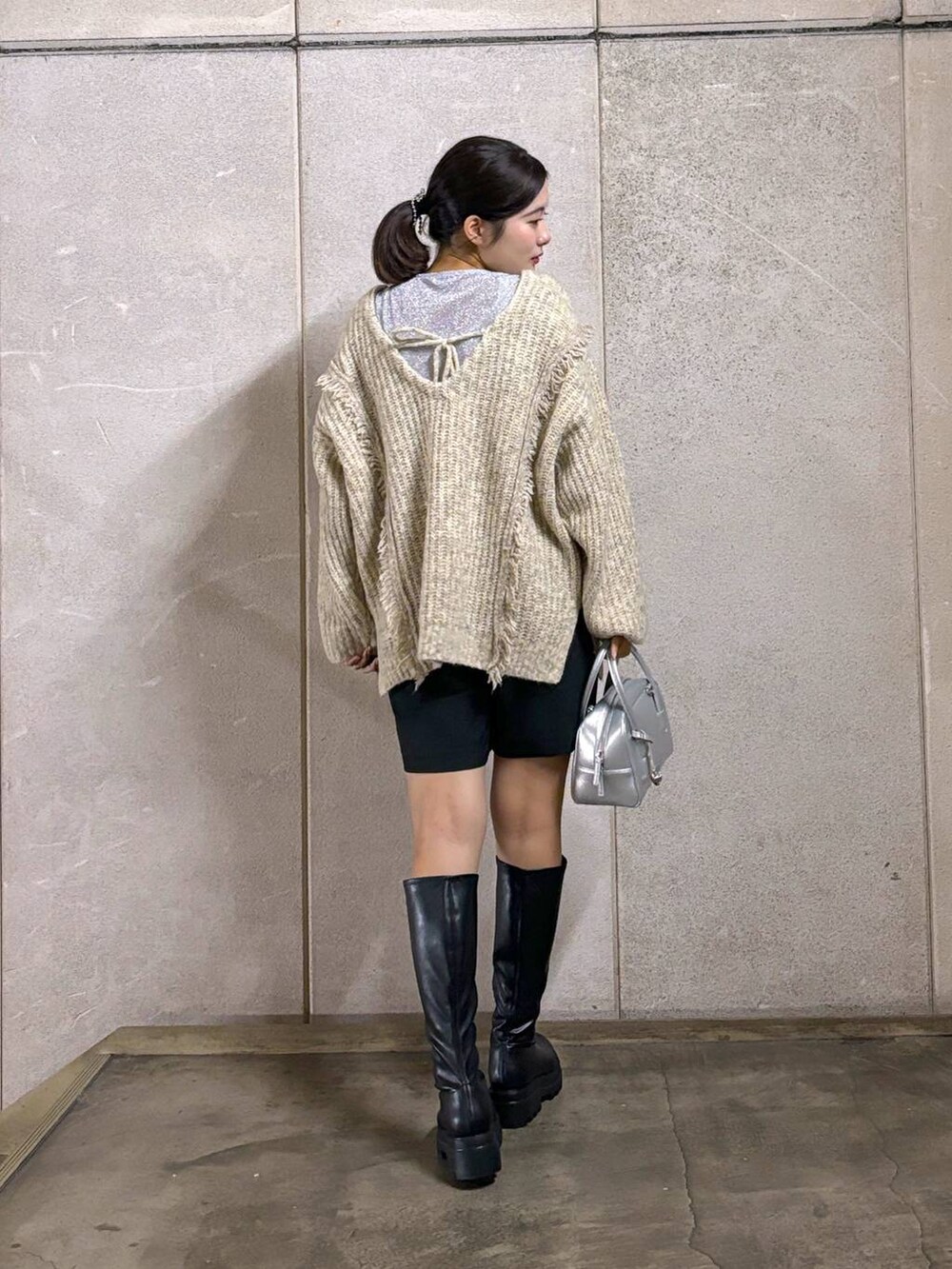 ホワイト系のニット/セーター、ブラック系のブーツ、シルバー系のボストンバッグを着用したレディースの秋コーディネートの3枚目の写真