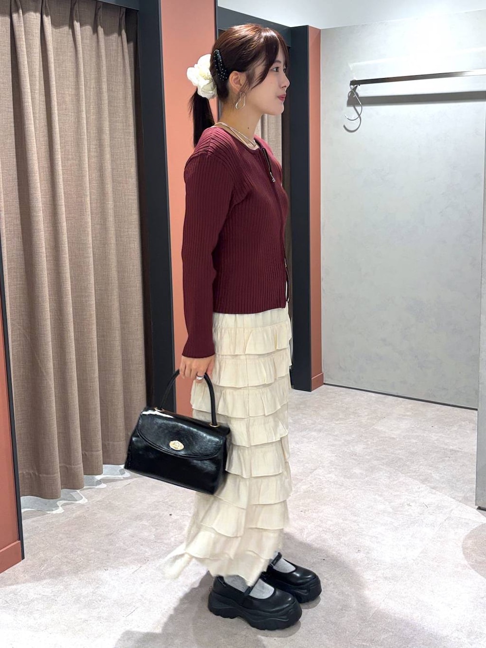 ブラック系のスニーカー、ブラック系のボストンバッグ、ホワイト系のスカートを着用したレディースの秋コーディネートの2枚目の写真