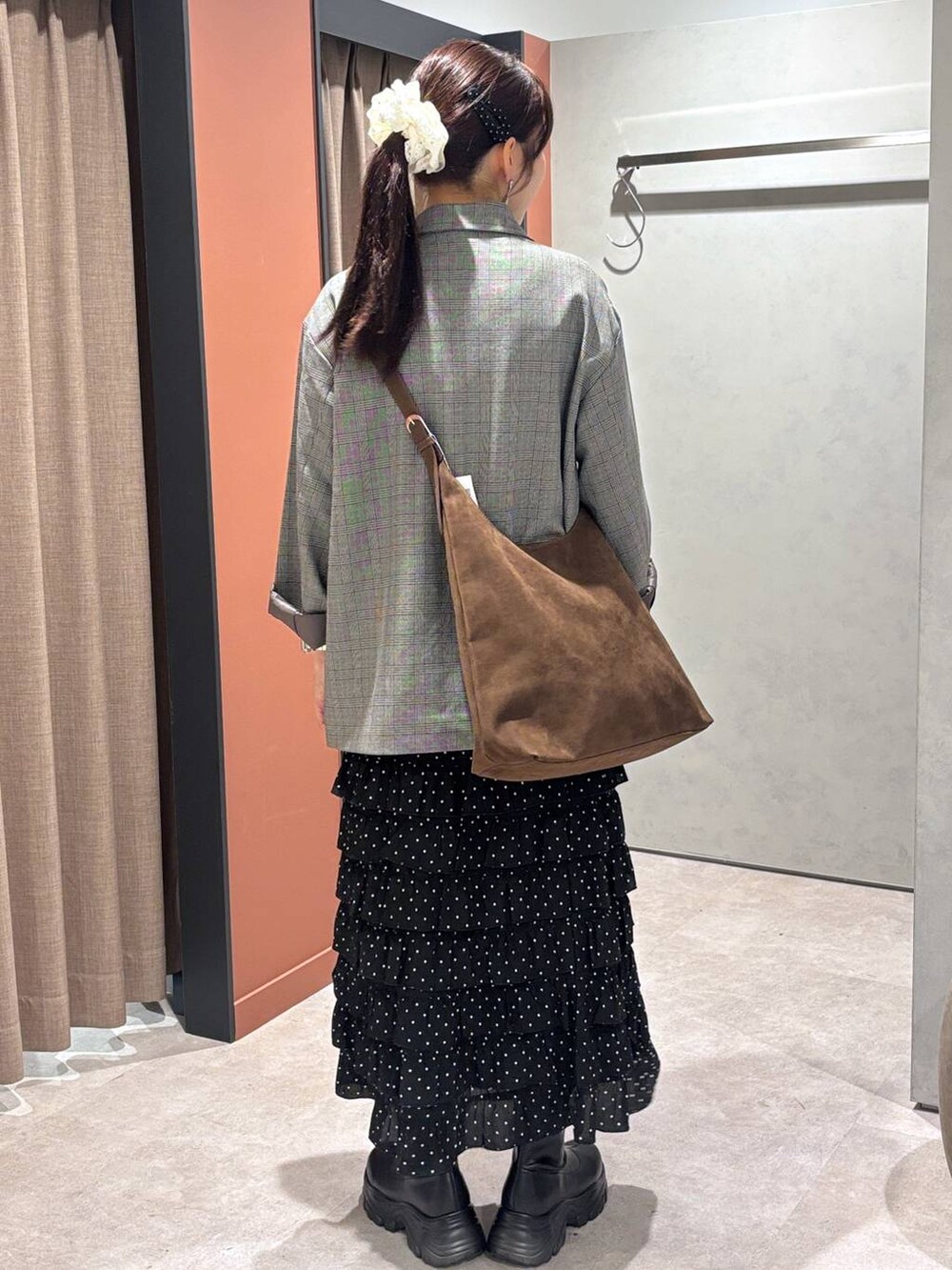 ブラウン系のショルダーバッグ、ブラック系のブーツ、グレー系のテーラードジャケットを着用したレディースの秋コーディネートの3枚目の写真