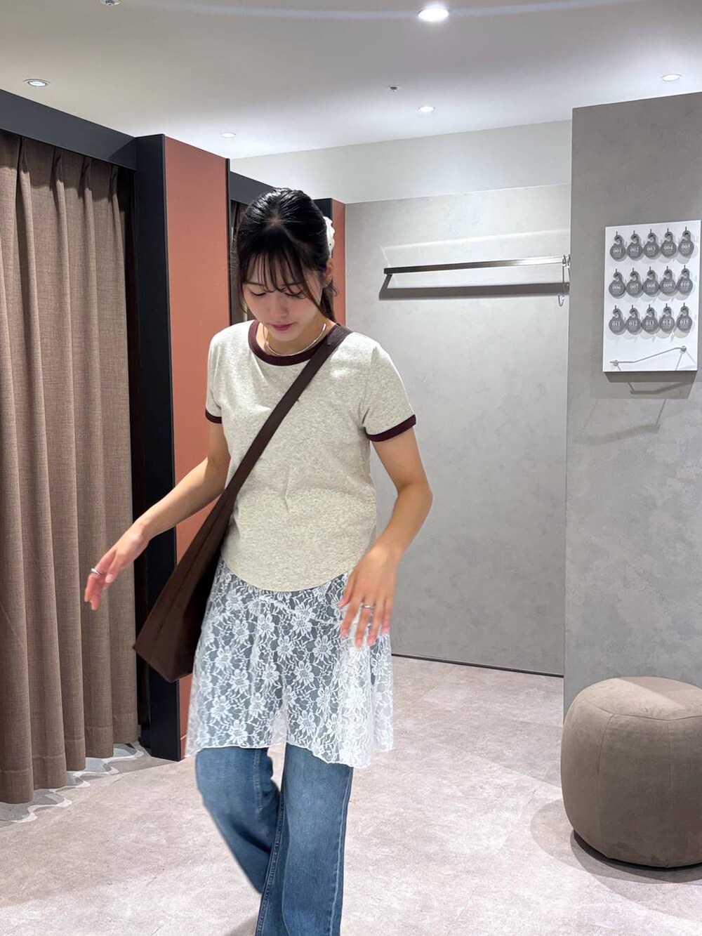 ブラウン系のショルダーバッグ、グレー系のTシャツ/カットソー、ブルー系のデニムパンツを着用したレディースの夏コーディネートの5枚目の写真