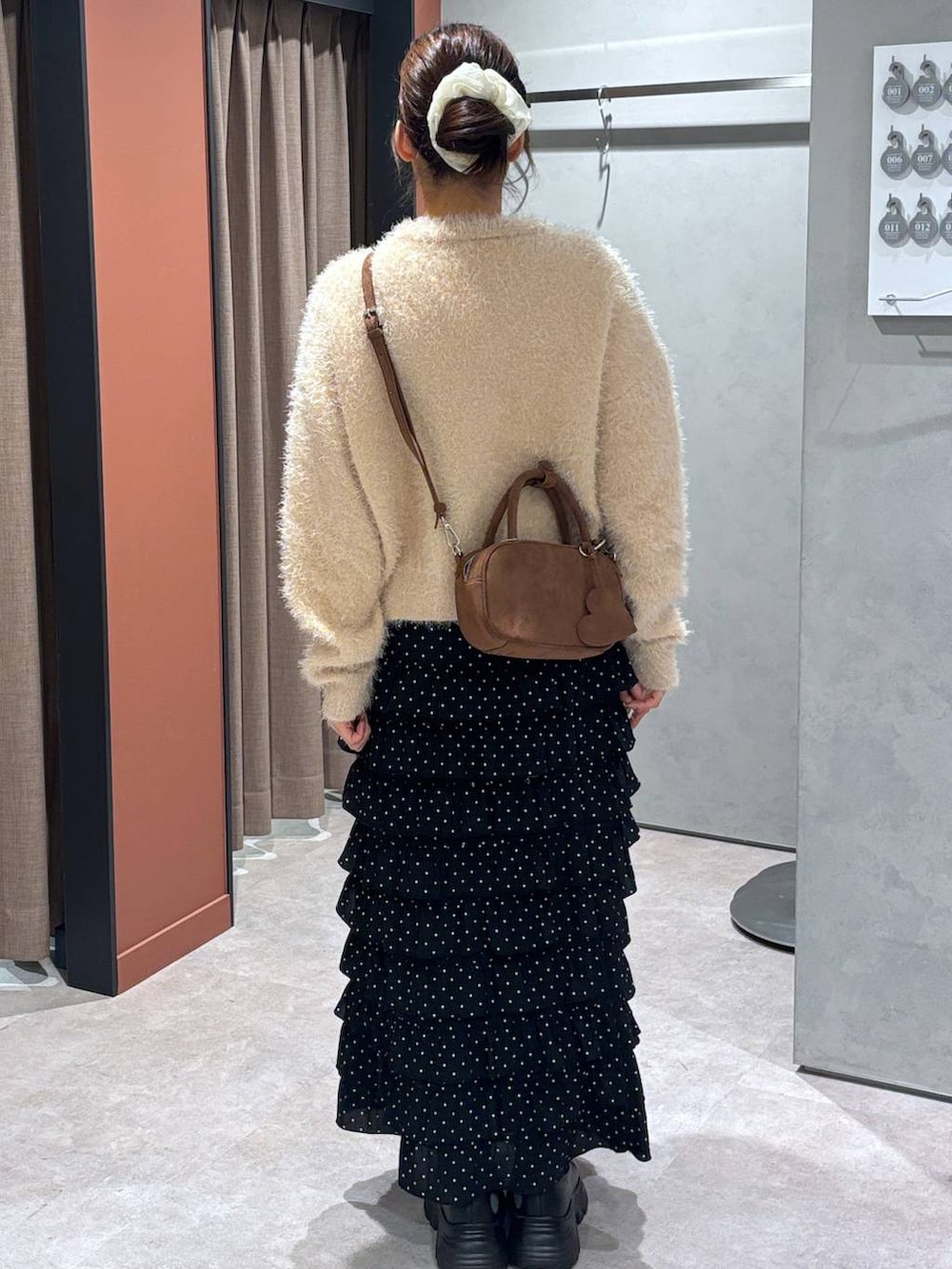 ブラック系のブーツ、その他のスカート、ブラウン系のボストンバッグを着用したレディースの秋コーディネートの3枚目の写真