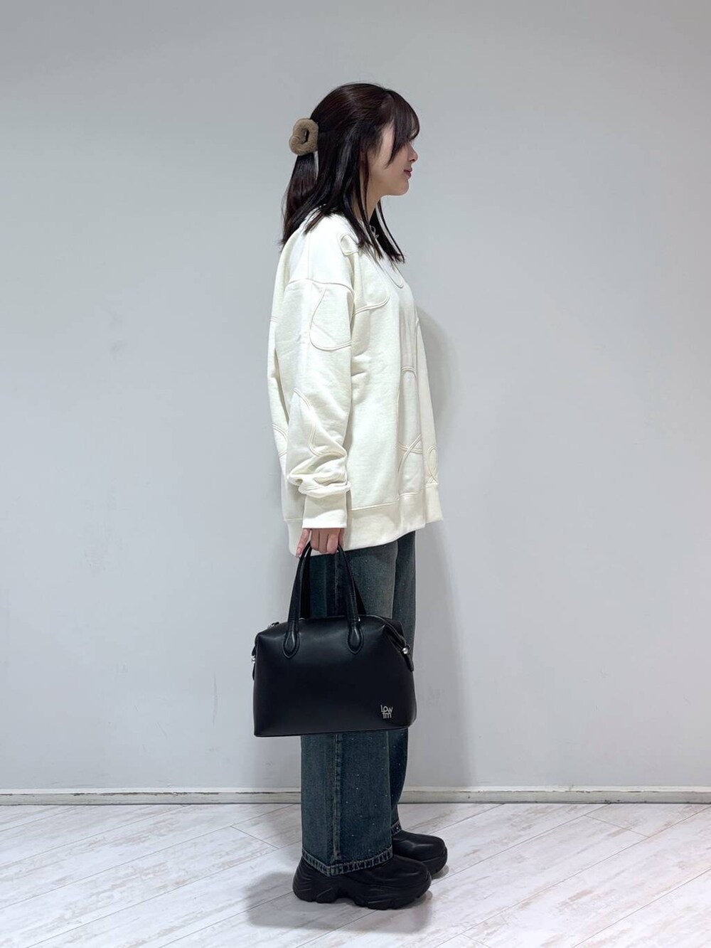 ブラック系のブーツ、ブルー系のデニムパンツ、ブラック系のショルダーバッグを着用したレディースの冬コーディネートの2枚目の写真