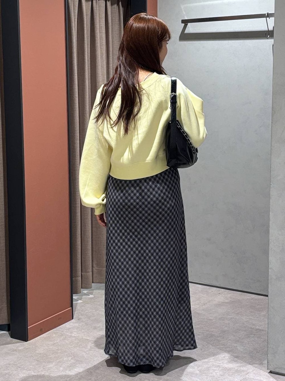 ブラック系のショルダーバッグ、ブラック系のパンプス、イエロー系のスウェットを着用したレディースの春コーディネートの3枚目の写真