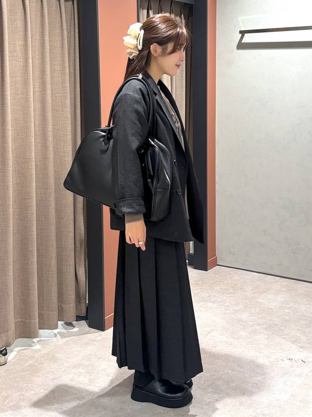 グレー系のテーラードジャケット、グレー系のスカート、ブラック系のボストンバッグを着用したレディースの秋コーディネートの2枚目の写真