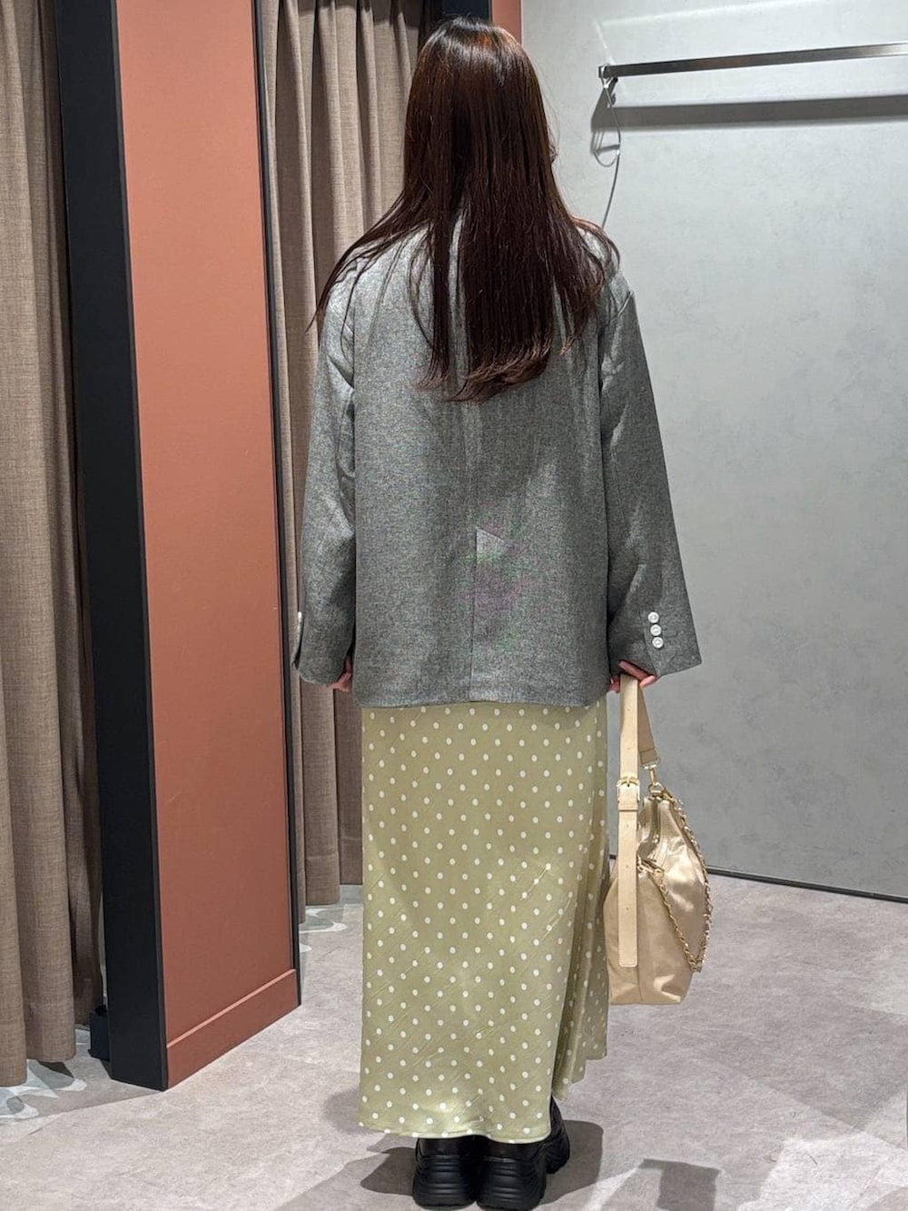 ベージュ系のスカート、グレー系のテーラードジャケット、ベージュ系のショルダーバッグを着用したレディースの冬コーディネートの3枚目の写真