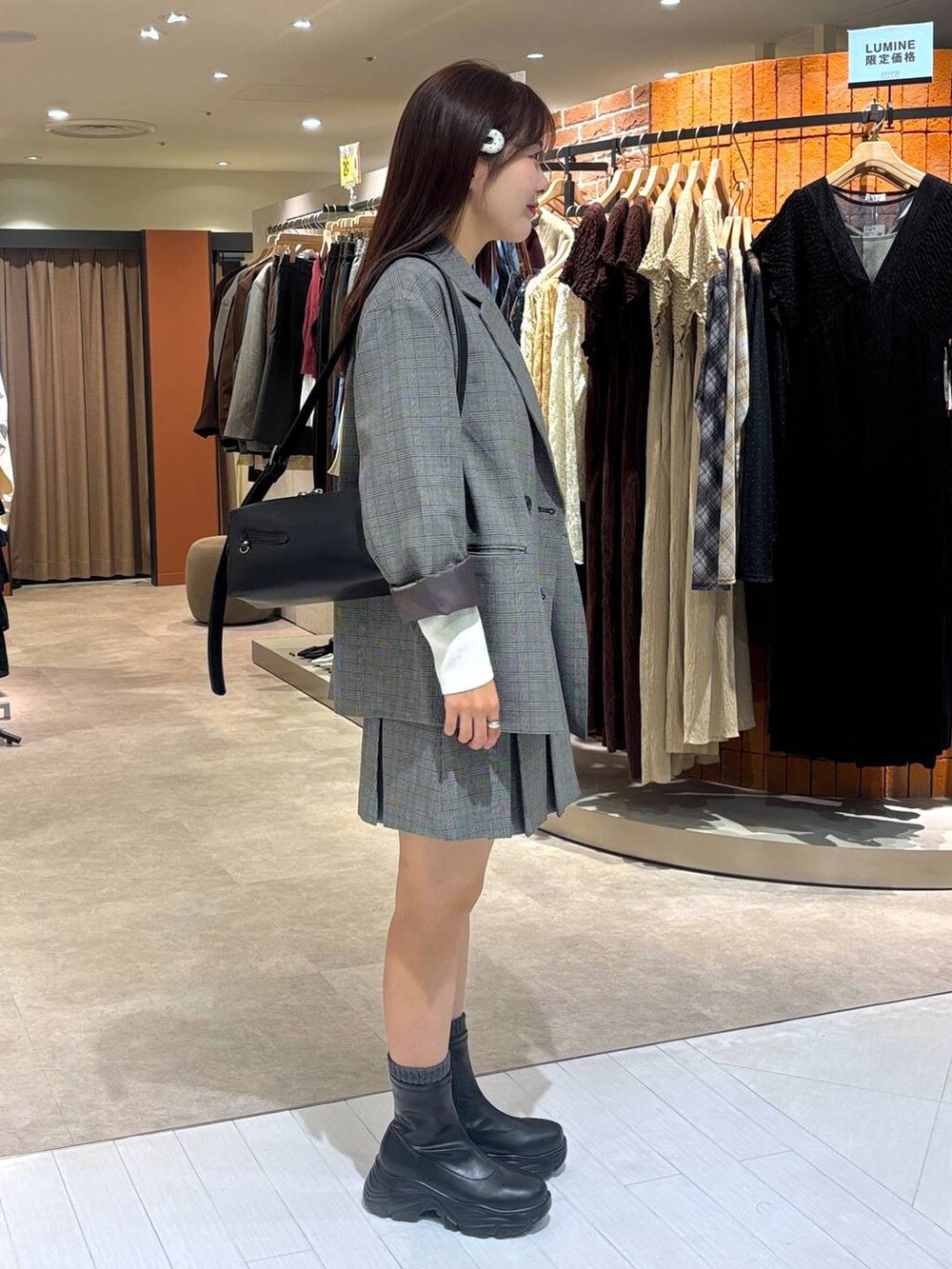 ブラック系のブーツ、グレー系のテーラードジャケット、その他のスカートを着用したレディースの秋コーディネートの2枚目の写真