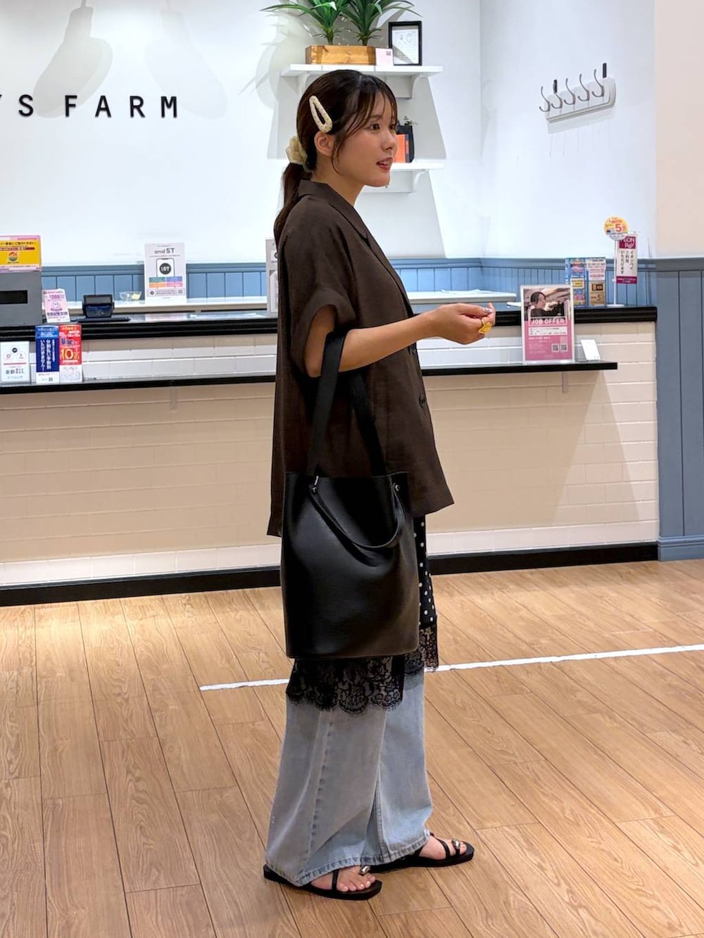 ブルー系のデニムパンツ、ブラウン系のテーラードジャケット、ブラック系のサンダルを着用したレディースの夏コーディネートの2枚目の写真