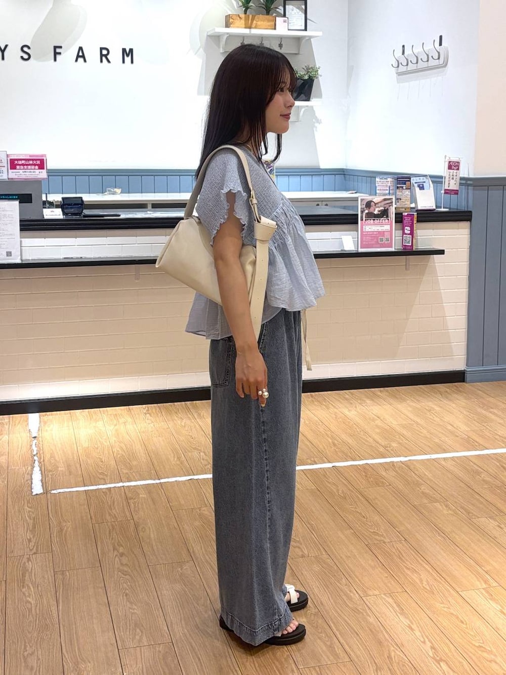 ブルー系のデニムパンツ、ホワイト系のサンダル、ホワイト系のショルダーバッグを着用したレディースの春コーディネートの2枚目の写真