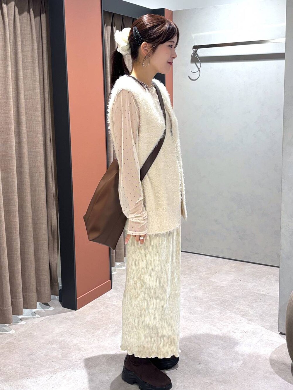 ホワイト系のベスト、ブラウン系のショルダーバッグ、ホワイト系のスカートを着用したレディースの秋コーディネートの2枚目の写真