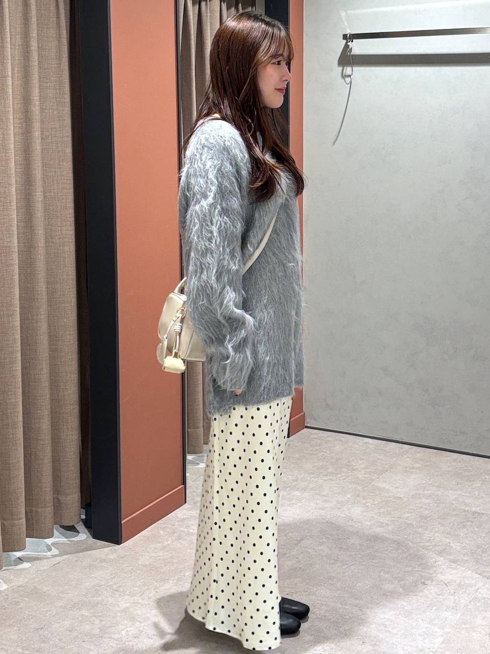 ホワイト系のスカート、ホワイト系のボストンバッグ、ブラック系のブーツを着用したレディースの冬コーディネートの2枚目の写真