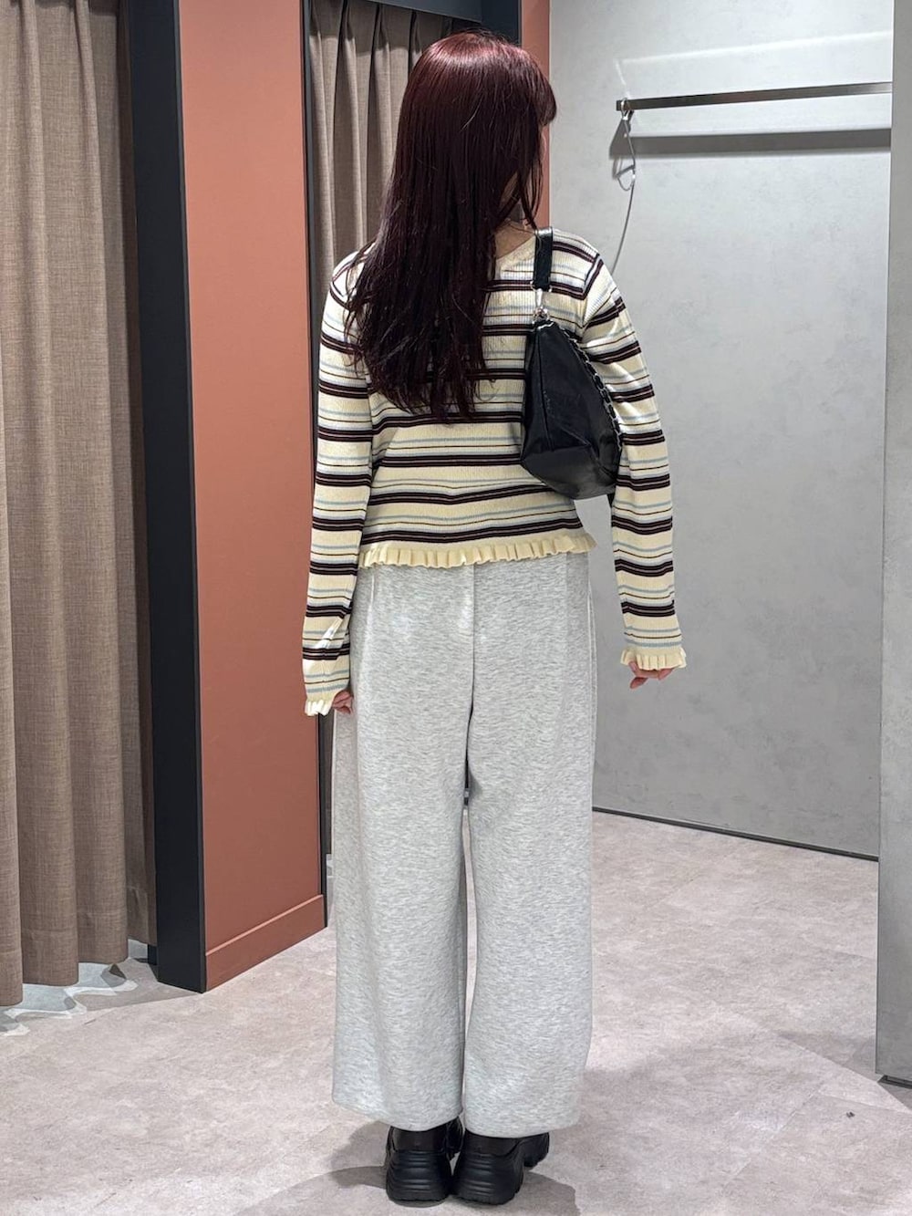 グレー系のスウェットパンツ、ブラック系のショルダーバッグ、ブラウン系のローファーを着用したレディースの冬コーディネートの2枚目の写真