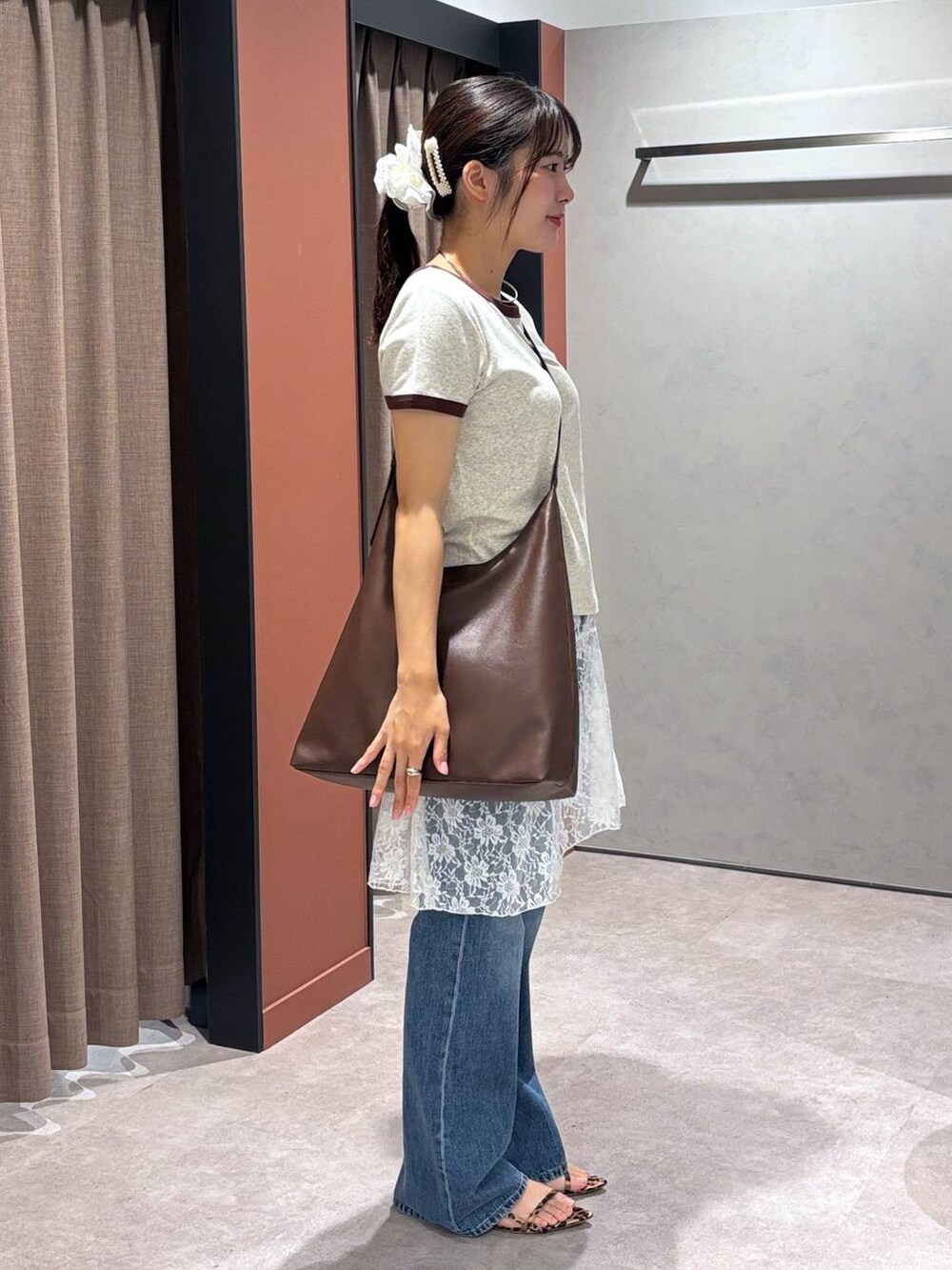 ブラウン系のショルダーバッグ、グレー系のTシャツ/カットソー、ブルー系のデニムパンツを着用したレディースの夏コーディネートの2枚目の写真