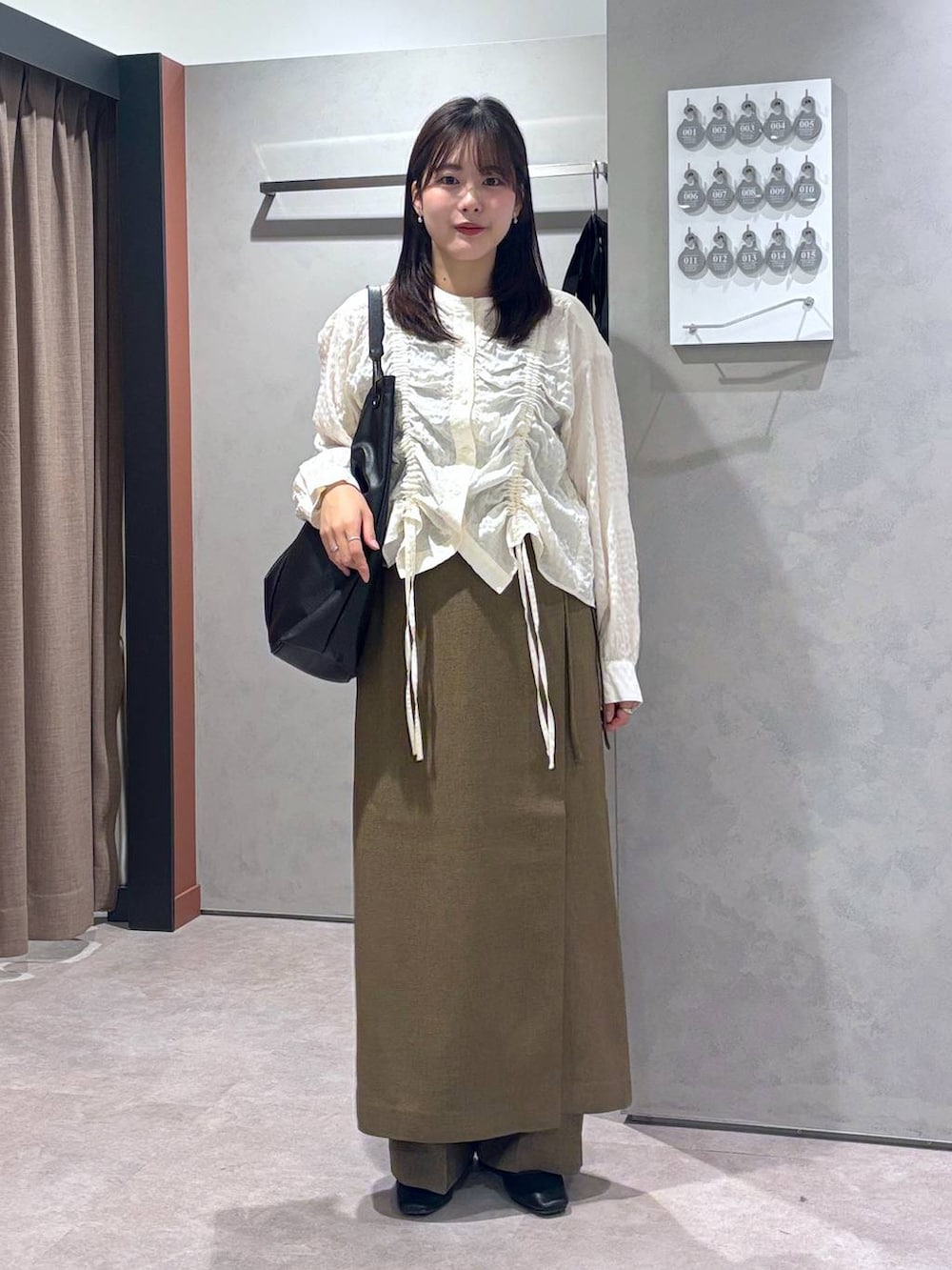 ブラウン系のスラックス、ブラウン系のスカート、ブラック系のトートバッグを着用したレディースの春コーディネートの4枚目の写真