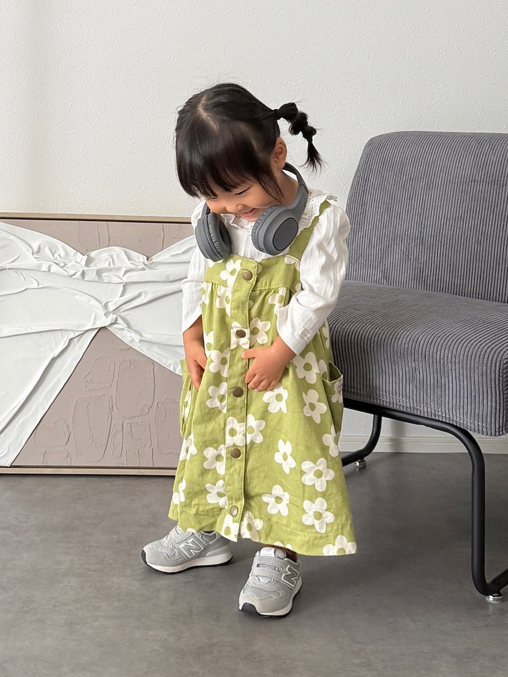 グリーン系のジャンパースカート、グレー系のスニーカー、ホワイト系のTシャツ/カットソーを着用したキッズの秋コーディネートの2枚目の写真