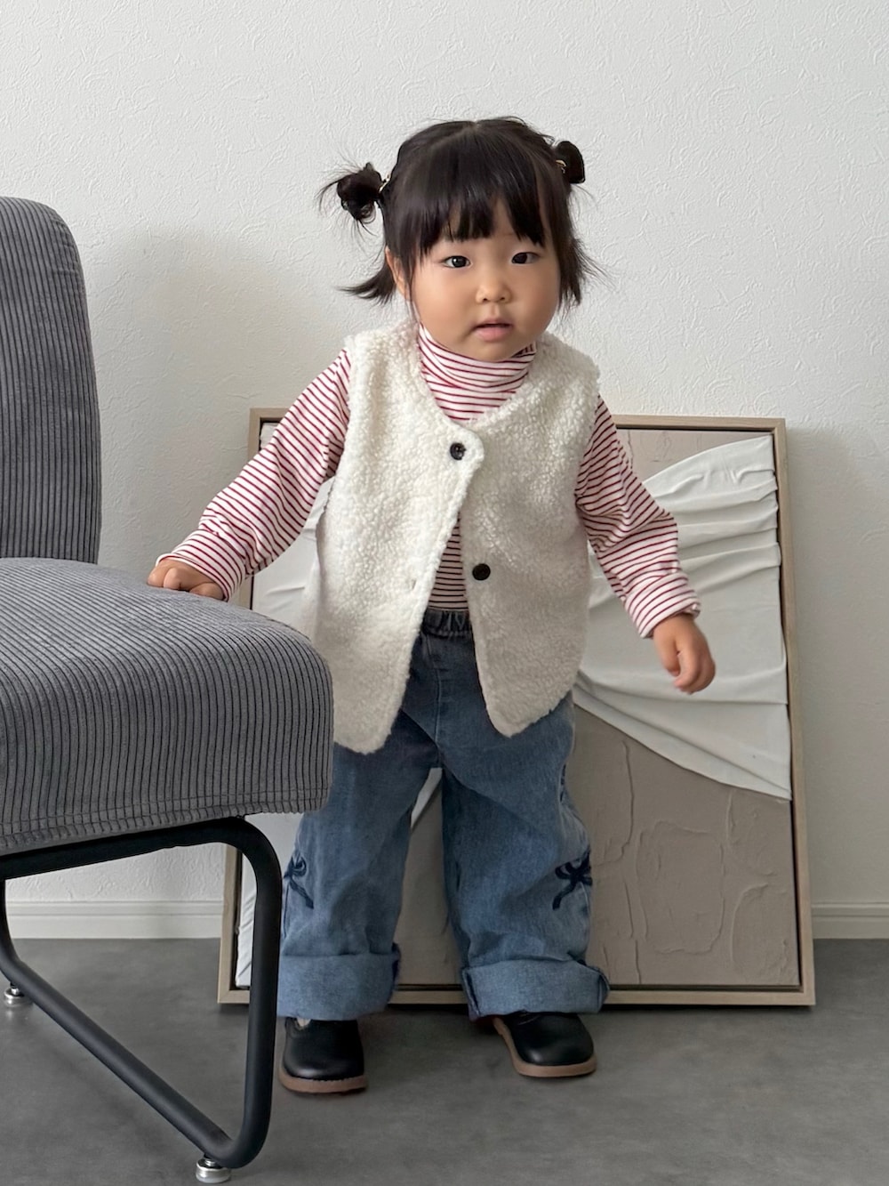 ホワイト系のベスト、レッド系のTシャツ/カットソー、ブルー系のデニムパンツを着用したキッズの秋コーディネートの3枚目の写真