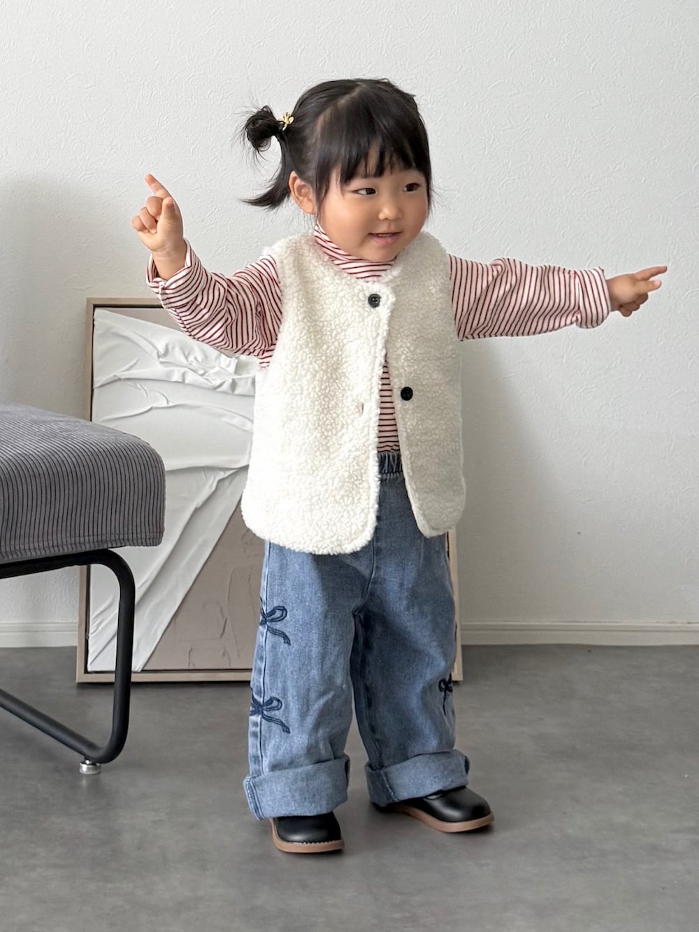 ホワイト系のベスト、レッド系のTシャツ/カットソー、ブルー系のデニムパンツを着用したキッズの秋コーディネートの2枚目の写真