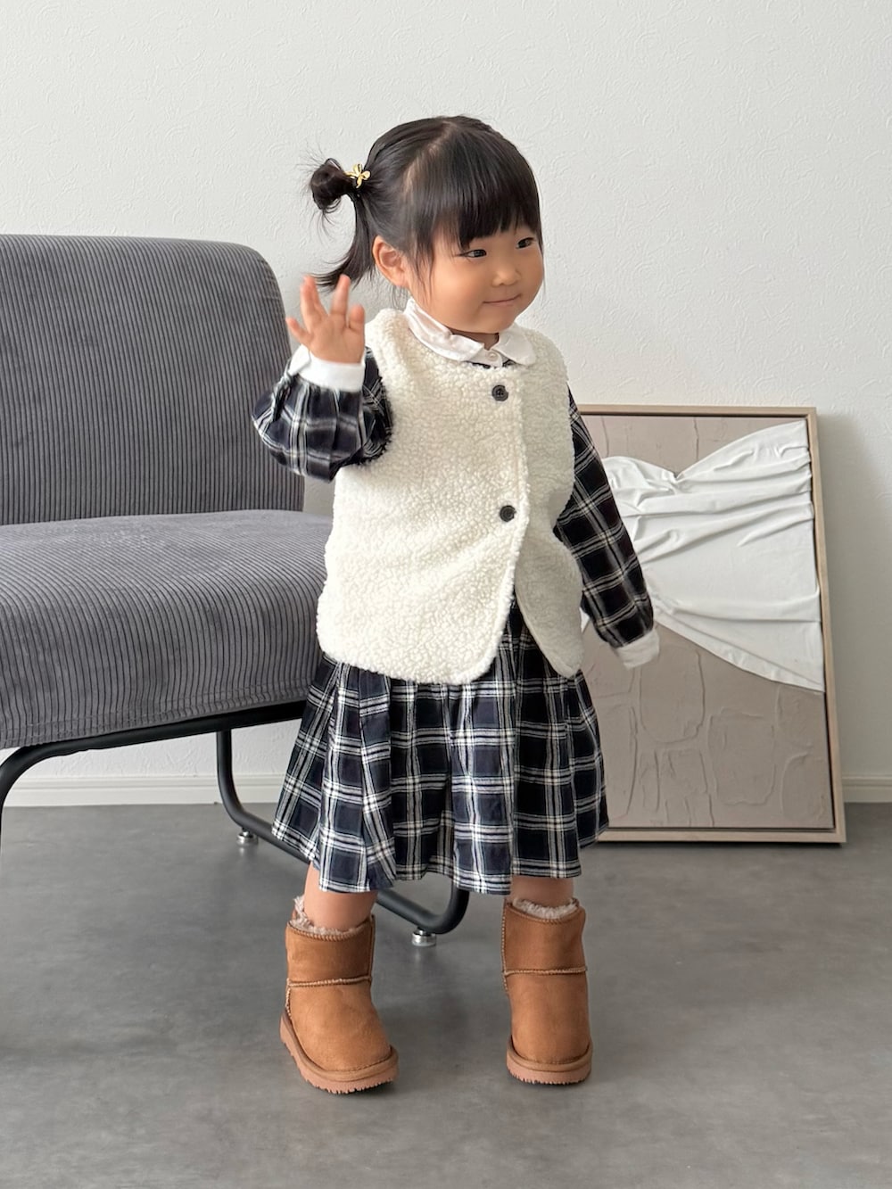 ブルー系のシャツワンピース、イエロー系のブーツ、ホワイト系のベストを着用したキッズの秋コーディネートの2枚目の写真