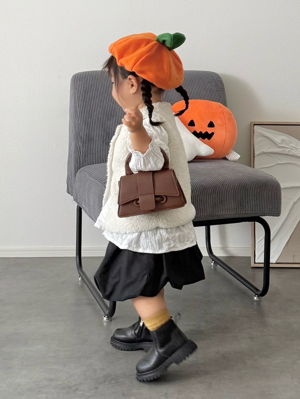 ブラック系のスカート、ホワイト系のベストを着用したキッズの秋コーディネートの2枚目の写真