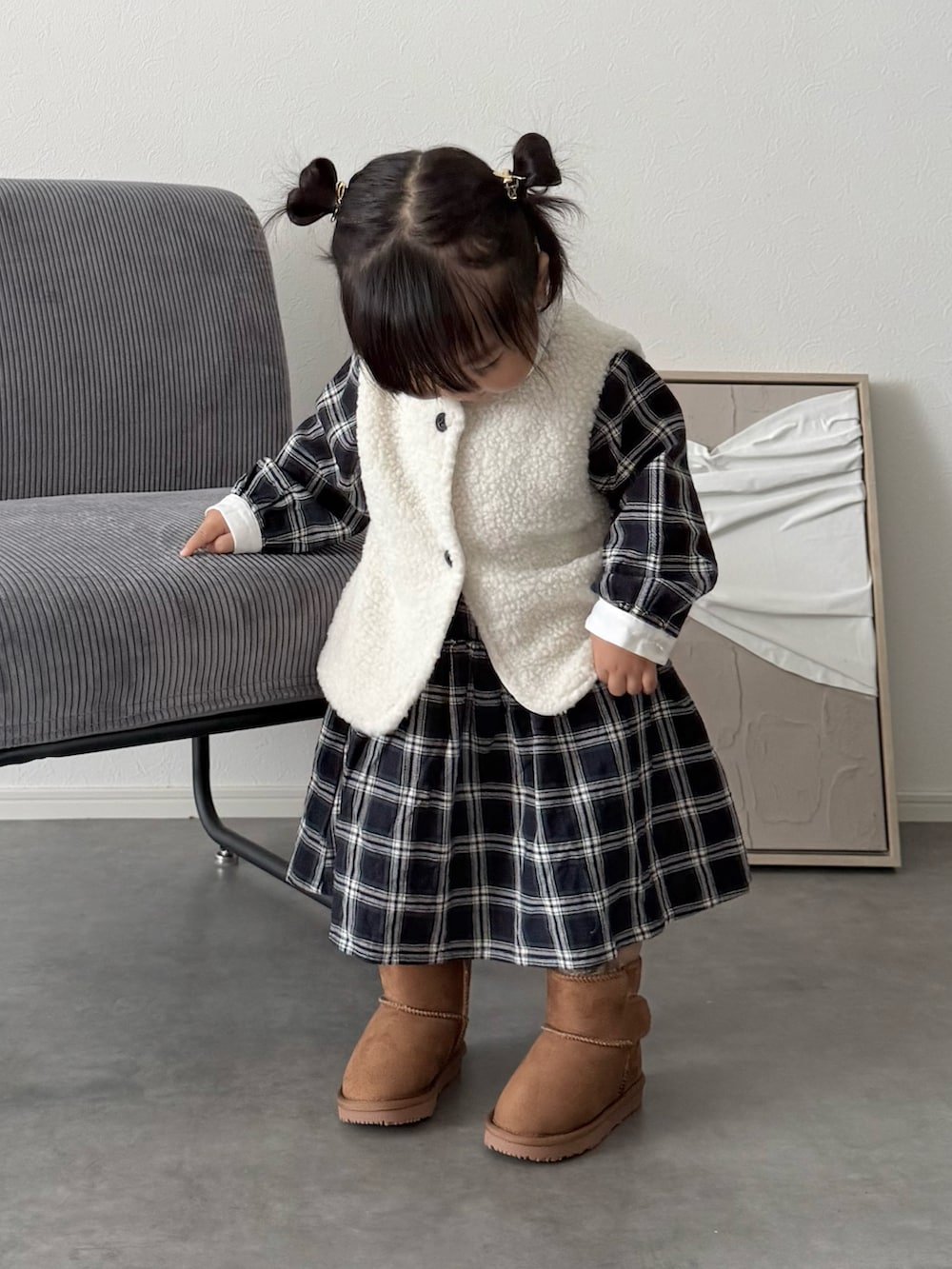 ブルー系のシャツワンピース、イエロー系のブーツ、ホワイト系のベストを着用したキッズの秋コーディネートの3枚目の写真