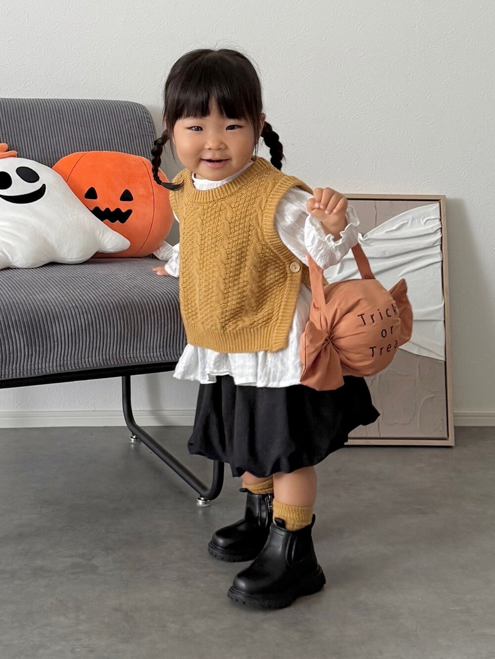 ブラック系のスカート、イエロー系のニット/セーター、オレンジ系の雑貨/ホビーを着用したキッズの秋コーディネートの4枚目の写真