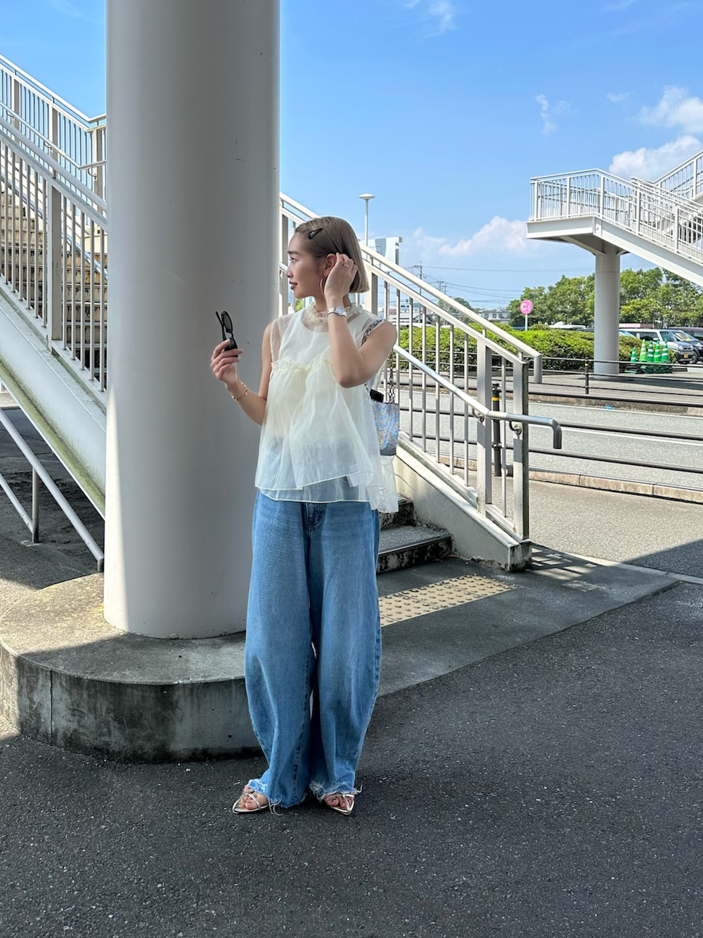 ホワイト系のベスト、ブルー系のデニムパンツを着用したレディースの夏コーディネートの2枚目の写真