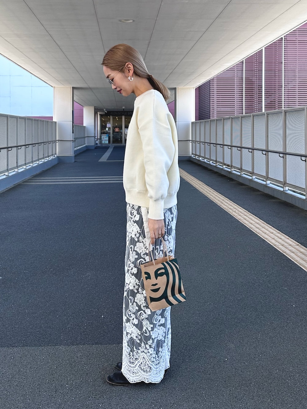 ホワイト系のニット/セーター、ホワイト系のスカート、ブルー系のデニムパンツを着用したレディースの冬コーディネートの2枚目の写真