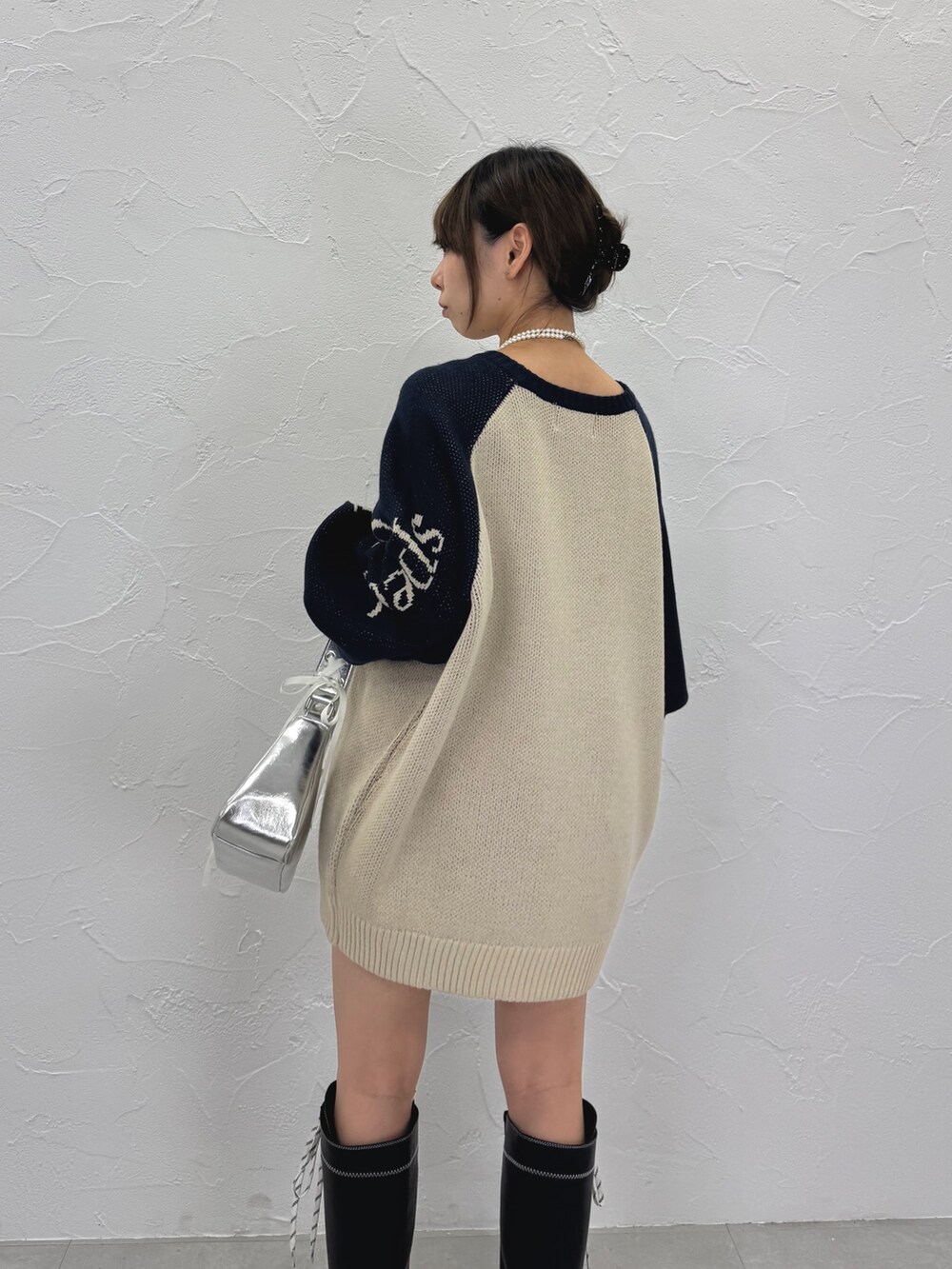 ホワイト系のニット/セーター、ブラック系のブーツ、シルバー系のハンドバッグを着用したレディースの秋コーディネートの5枚目の写真