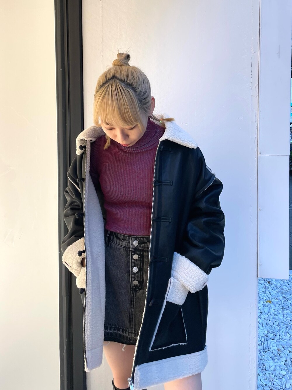 ブラック系のムートンコート、ブラック系のデニムパンツ、レッド系のニット/セーターを着用したレディースの夏コーディネートの6枚目の写真