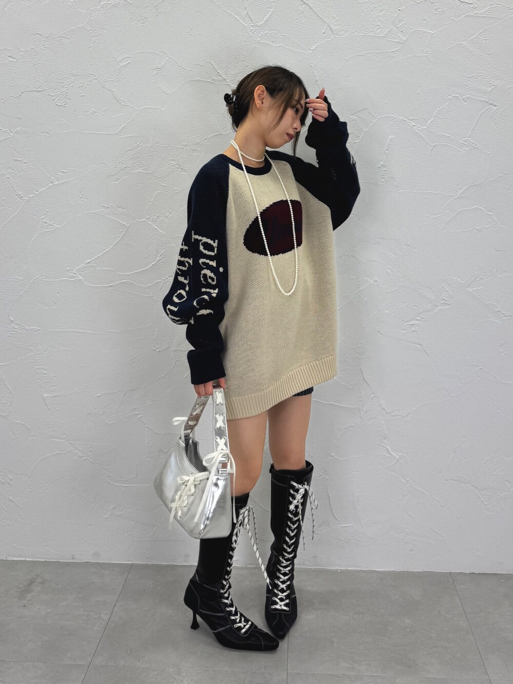 ホワイト系のニット/セーター、ブラック系のブーツ、シルバー系のハンドバッグを着用したレディースの秋コーディネートの2枚目の写真