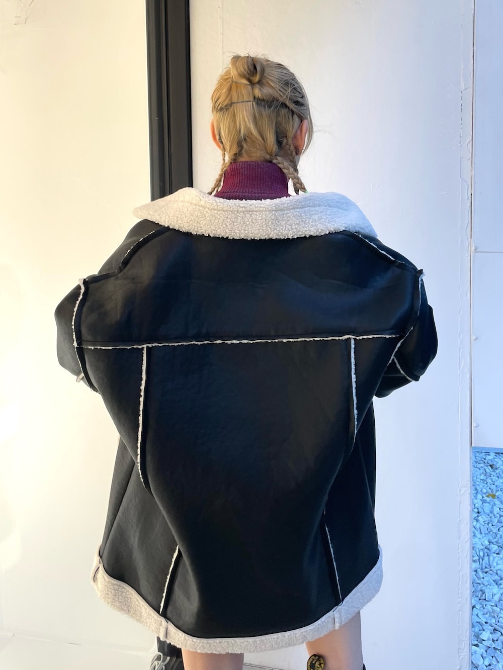 ブラック系のムートンコート、ブラック系のデニムパンツ、レッド系のニット/セーターを着用したレディースの夏コーディネートの8枚目の写真