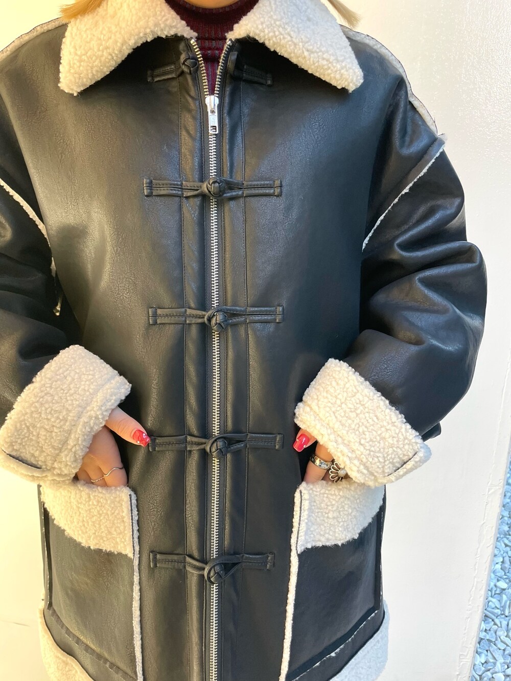 ブラック系のムートンコート、ブラック系のデニムパンツ、レッド系のニット/セーターを着用したレディースの夏コーディネートの9枚目の写真