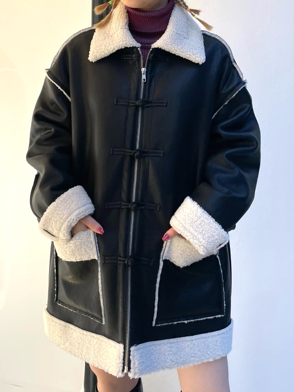 ブラック系のムートンコート、ブラック系のデニムパンツ、レッド系のニット/セーターを着用したレディースの夏コーディネートの5枚目の写真