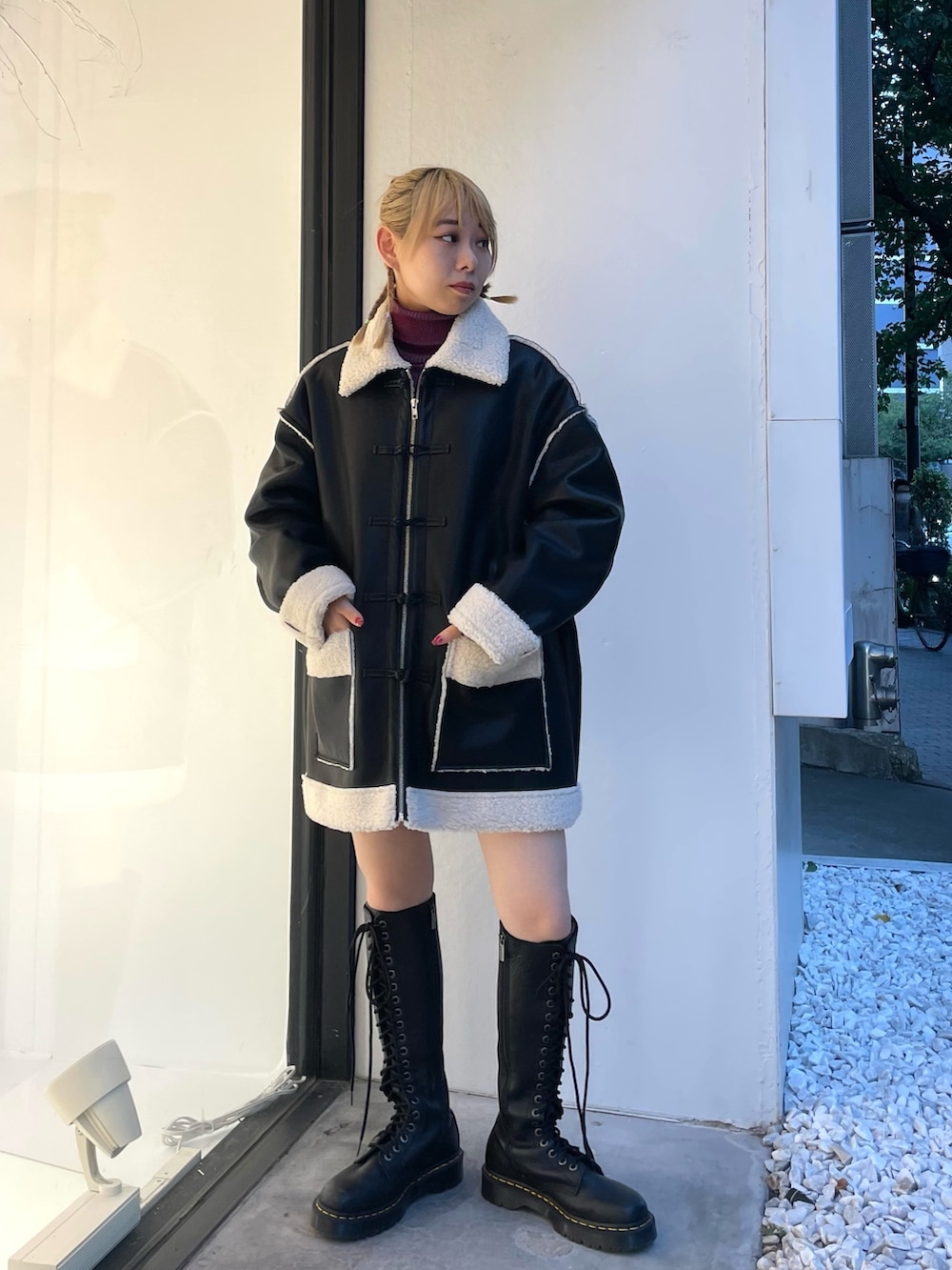 ブラック系のムートンコート、ブラック系のデニムパンツ、レッド系のニット/セーターを着用したレディースの夏コーディネートの2枚目の写真