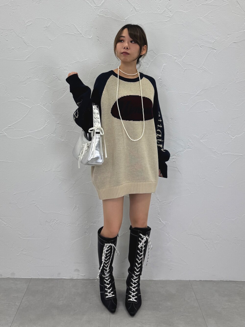 ホワイト系のニット/セーター、ブラック系のブーツ、シルバー系のハンドバッグを着用したレディースの秋コーディネートの3枚目の写真