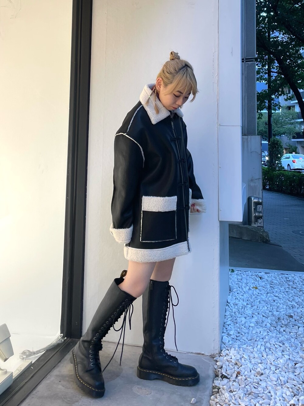 ブラック系のムートンコート、ブラック系のデニムパンツ、レッド系のニット/セーターを着用したレディースの夏コーディネートの4枚目の写真