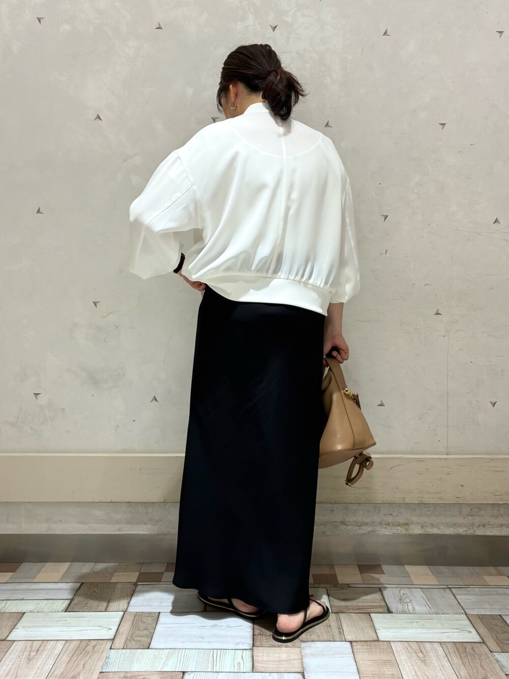 ホワイト系のブルゾン、ブラック系のスカートを着用したレディースの春コーディネートの2枚目の写真