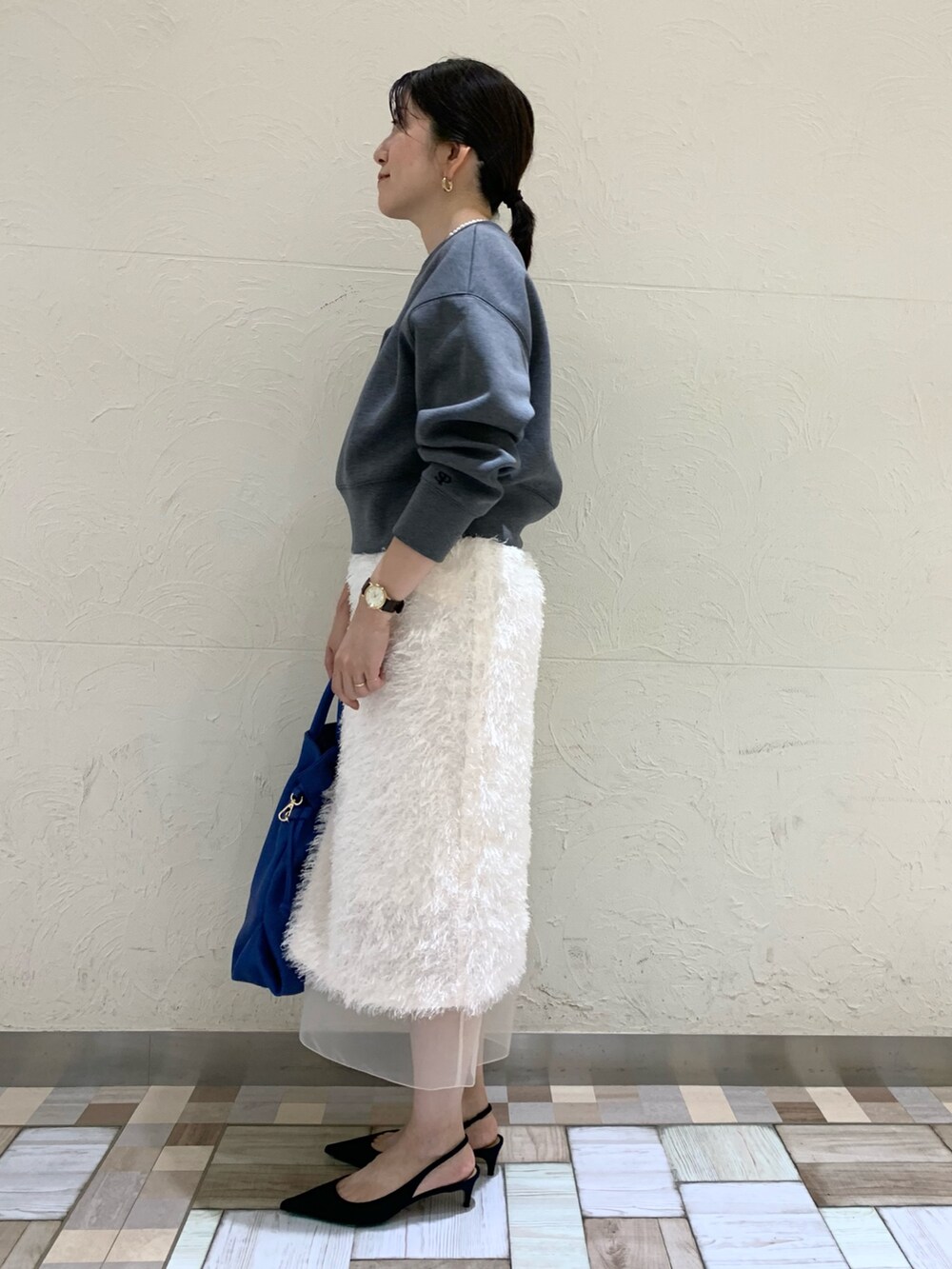 グレー系のTシャツ/カットソー、ホワイト系のスカート、ブルー系のショルダーバッグを着用したレディースの秋コーディネートの2枚目の写真