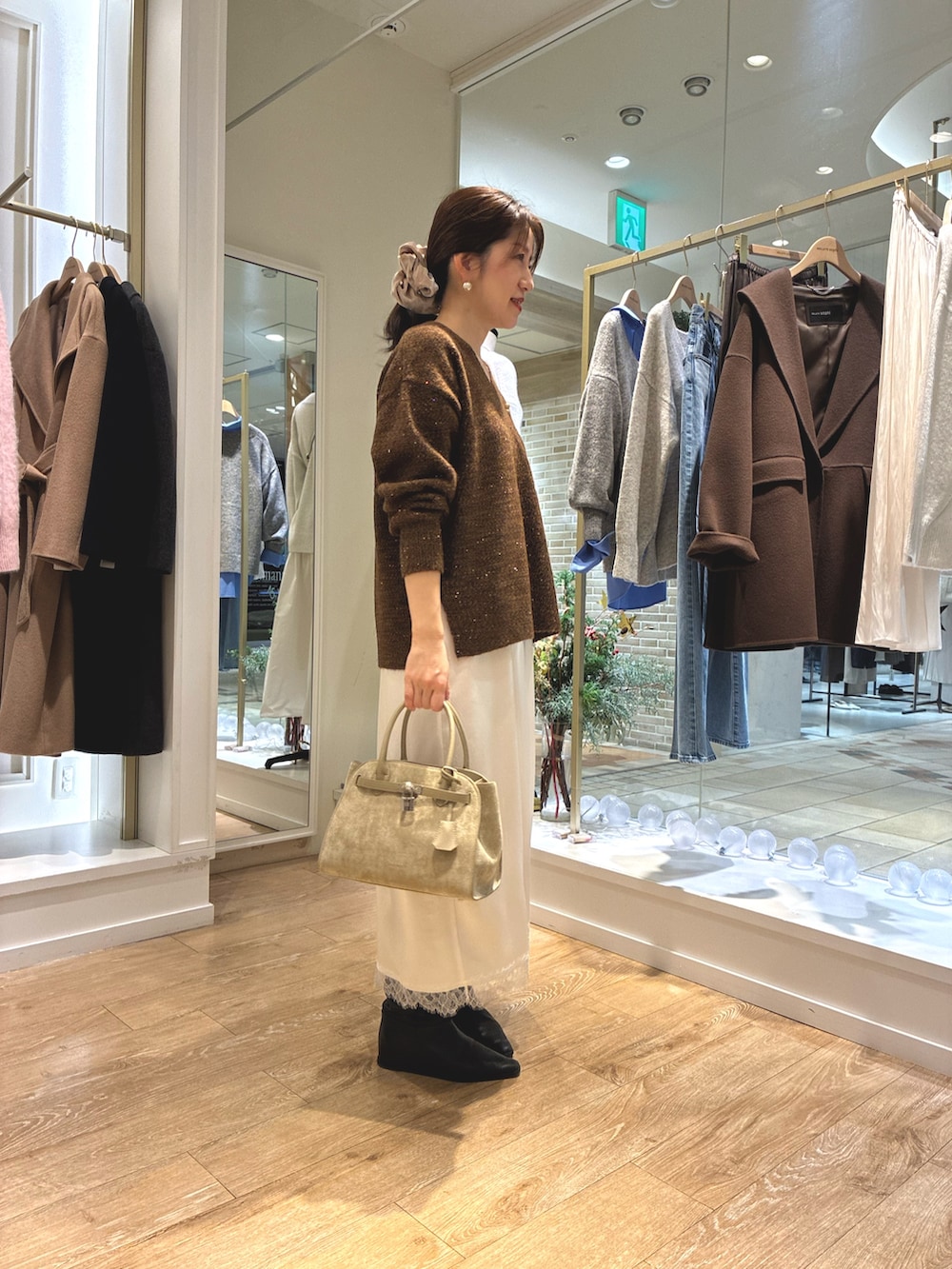 ブラウン系のニット/セーター、ホワイト系のワンピース、ベージュ系のトートバッグを着用したレディースの冬コーディネートの5枚目の写真