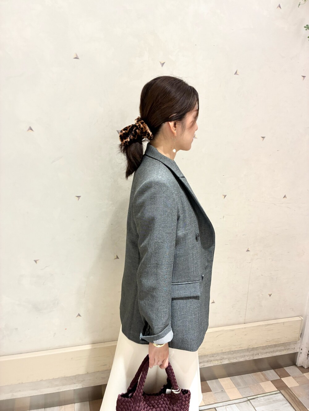 グレー系のテーラードジャケット、ホワイト系のスカート、イエロー系のニット/セーターを着用したレディースの秋コーディネートの5枚目の写真