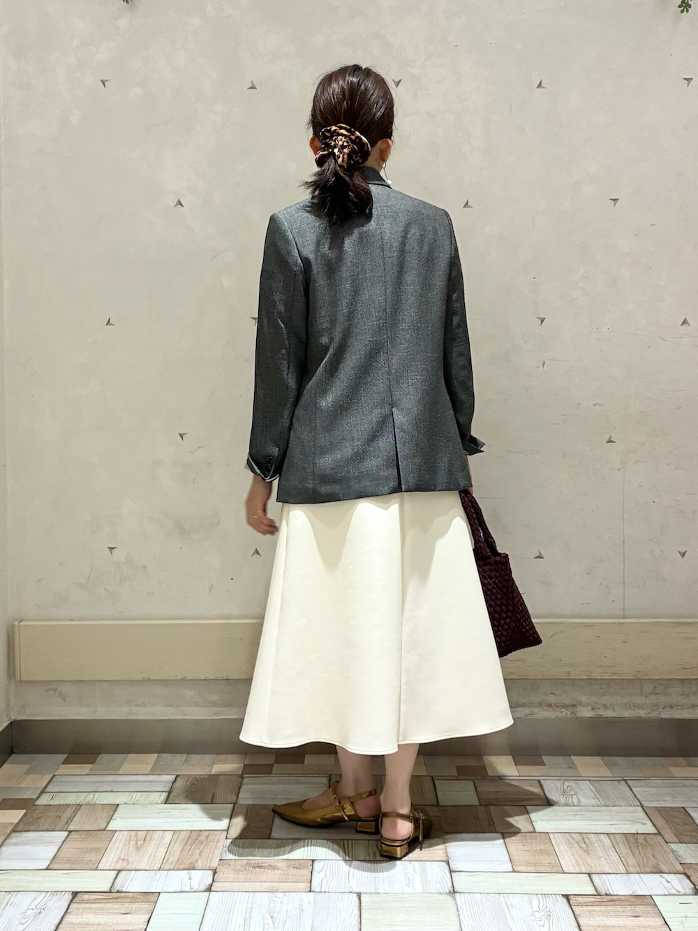 グレー系のテーラードジャケット、ホワイト系のスカート、イエロー系のニット/セーターを着用したレディースの秋コーディネートの4枚目の写真