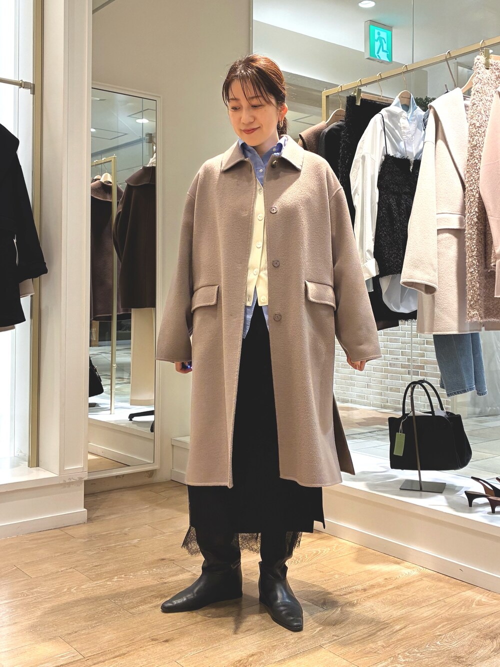 グリーン系のステンカラーコート、ブラック系のスカート、ブルー系のシャツ/ブラウスを着用したレディースの秋コーディネートの9枚目の写真
